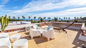 A rooftop terrace with white outdoor furniture, palm trees, and a view of the ocean. - Casa Ibrahim, Frontline Beach House (Torreguadiaro)