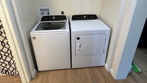 Un cuarto de lavandería con dos electrodomésticos blancos, uno con un panel de control y otro con una puerta.
