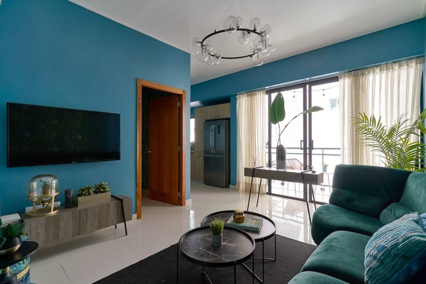 Een moderne woonkamer met een flatscreen televisie, een bank, een salontafel en een eethoek met een tafel en stoelen.