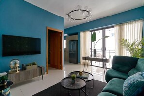 Ein modernes Wohnzimmer mit Flachbildfernseher, einer Couch, einem Couchtisch und einem Essbereich mit Tisch und Stühlen.
