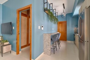 A modern kitchen with a bar area, a flat-screen TV, and a refrigerator. - [The~Natural~Blues] @DowntownSD +Pool+Gym+Centric (Santo Domingo)