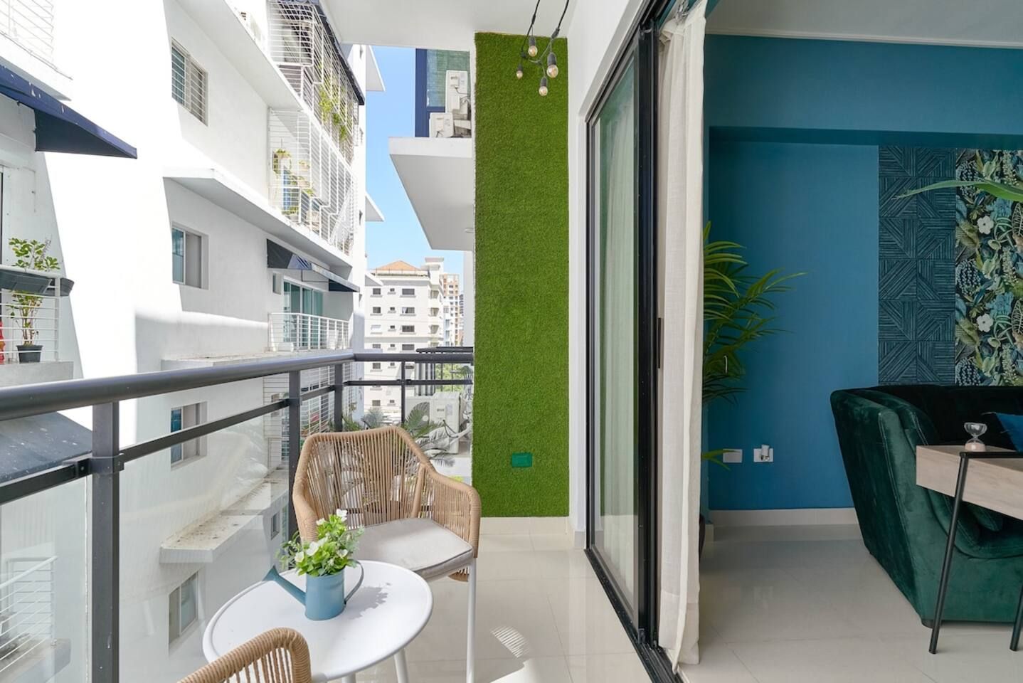 En balkon med fletstole, et lille bord og en potteplante.
