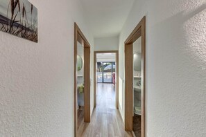 Ein Flur mit Holztüren, der zu einem Badezimmer und einem Wohnbereich führt.