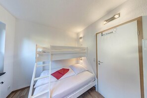 A bunk bed room with a door, a light fixture, and a wall socket.