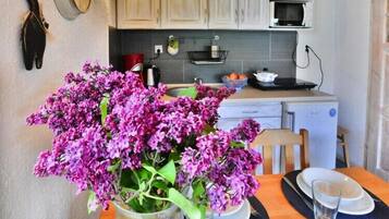 Une cuisine avec un vase de fleurs violettes sur la table, un four à micro-ondes et des placards.
