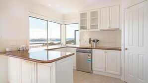 Una cucina moderna con mobili bianchi, lavastoviglie in acciaio inossidabile e una grande isola con piano di lavoro in granito.