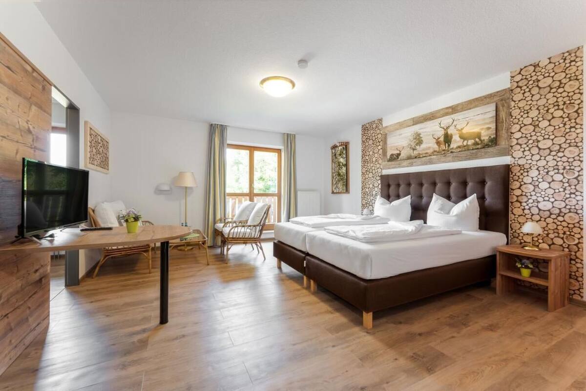 A hotel room with a large bed, a desk, a chair, a TV, and a stone wall.
