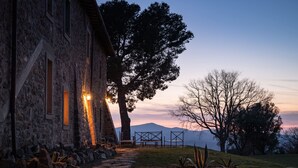 Un bâtiment en pierre avec un chemin également en pierre menant à un espace aménagé pour s’asseoir.