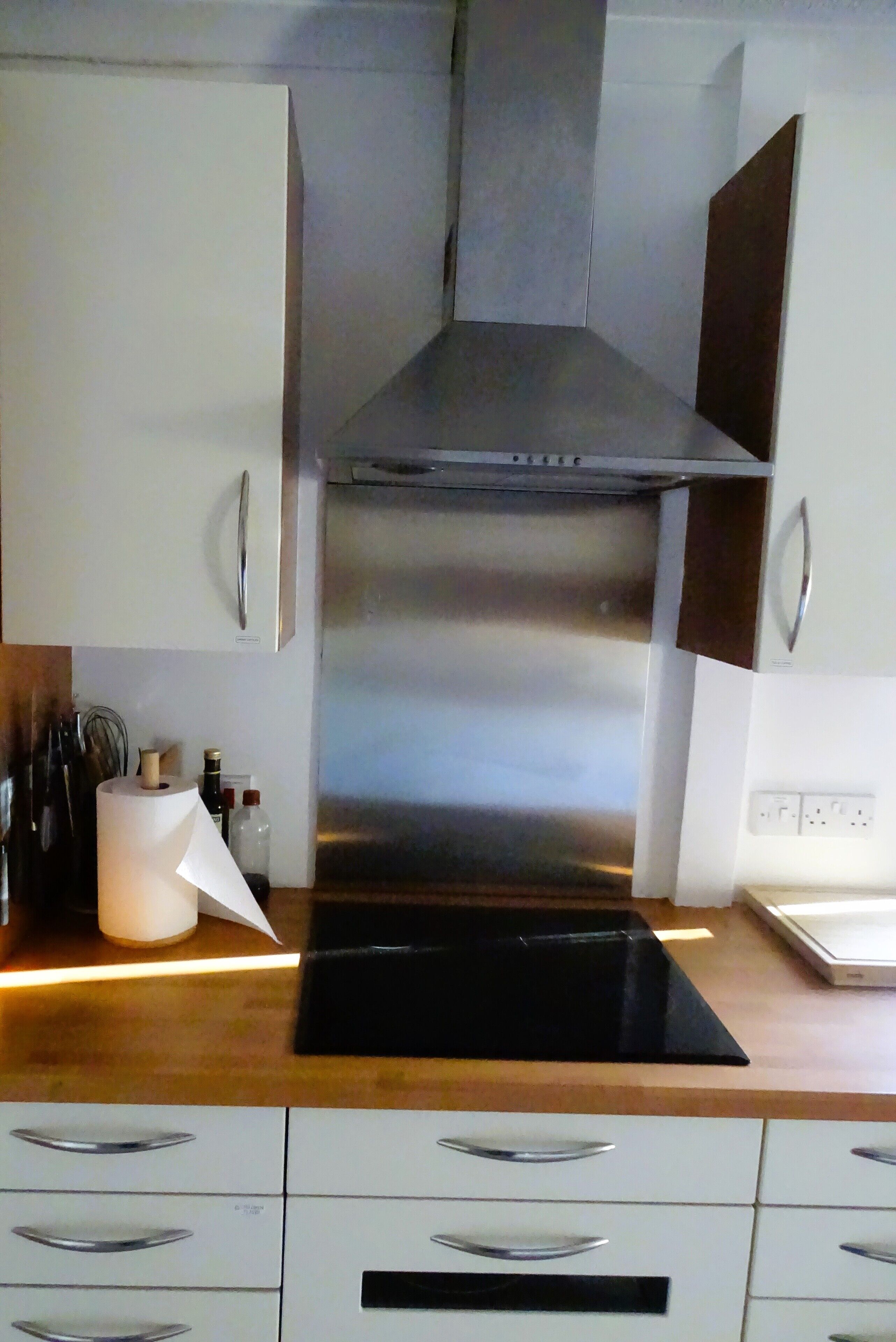 Una cocina moderna con electrodomésticos de acero inoxidable, armarios blancos y encimera negra.