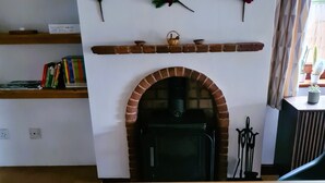 A cozy living room with a brick fireplace, a wooden table with candles, and a bookshelf with books and decorative items. - Lovely 3 bedroom detached house in Newbury (Newbury)