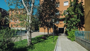 Un edificio con fachada de ladrillo, un camino pavimentado y una cerca de metal.