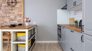 A kitchen with a brick wall, a wooden countertop, and grey cabinets. - Modern Apartment | 2 Bedrooms | Workspace | Katowice. (Katowice)