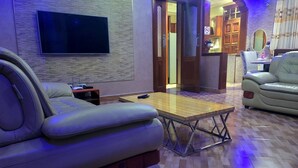 A modern living room with a flat-screen TV, leather sofas, a wooden coffee table, and a patterned floor. - Cape Villa (Arusha)