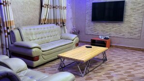 A living room with a sofa, a coffee table, and a TV mounted on the wall. - Cape Villa (Arusha)