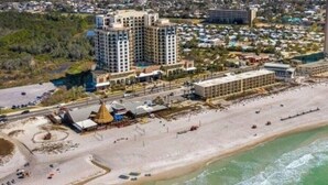 Ein Küstenhotel mit mehreren Hochhäusern, einem Strandzugang und einem Parkplatz.