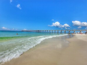 A beach with a pier extending into the ocean, clear skies, and calm waters. - Studio Partial Gulf View Steps to Beach &Pier Park (Panama City Beach)