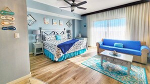 Une chambre à coucher avec un lit, un canapé bleu, une table basse et un ventilateur de plafond.