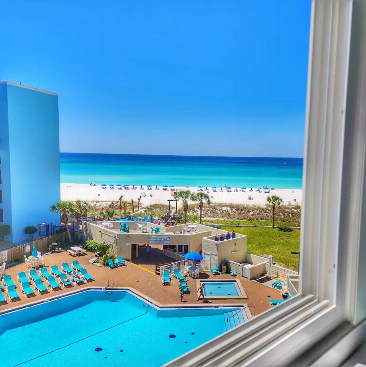 Poolbereich mit Liegestühlen und Blick auf einen Strand.