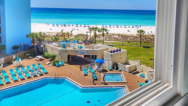 Un espace piscine avec des chaises longues et vue sur la plage.
