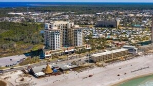 An aerial view of a coastal hotel with multiple high-rise buildings, a beachfront, and a surrounding urban area. - Balcony | Walk to Pier Park | Beach Across Street (Panama City Beach)