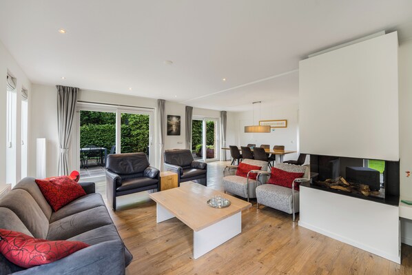 Una sala de estar moderna con sofá, sillones, una mesa de centro y chimenea.