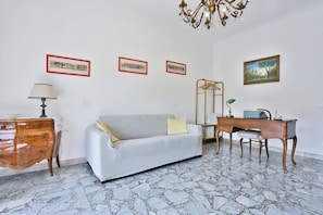 A room with a white sofa, a desk, a lamp, and framed pictures on the wall. - Bright apartment with a balcony overlooking Viale Augusto, in the heart of Fuorigrotta, in an elegant, recently renovated building with concierge service. The location is very convenient for reaching the historic center, the seafront, or Pozzuoli: the Me (Naples)
