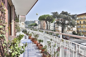 A balcony with potted plants, outdoor furniture, and a view of a cityscape with buildings and trees. - Bright apartment with a balcony overlooking Viale Augusto, in the heart of Fuorigrotta, in an elegant, recently renovated building with concierge service. The location is very convenient for reaching the historic center, the seafront, or Pozzuoli: the Me (Naples)