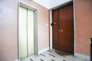 Un couloir avec une porte d’ascenseur fermée et une porte en bois fermée.