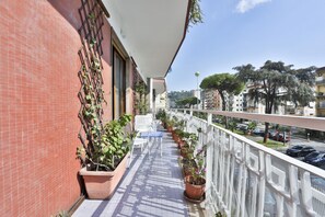 A balcony with potted plants, outdoor furniture, and a view of the street. - Bright apartment with a balcony overlooking Viale Augusto, in the heart of Fuorigrotta, in an elegant, recently renovated building with concierge service. The location is very convenient for reaching the historic center, the seafront, or Pozzuoli: the Me (Naples)