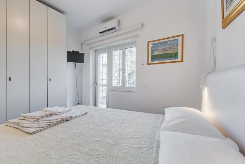 A bedroom with a bed, a wardrobe, a window, and a painting on the wall.