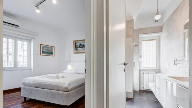 Ein Schlafzimmer mit einem Bett, einem Fenster und einer Tür zu einem Badezimmer.