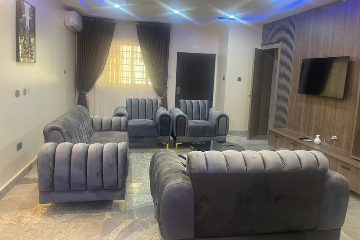 A modern living room with a sofa set, a flat-screen TV, and a wooden entertainment unit.