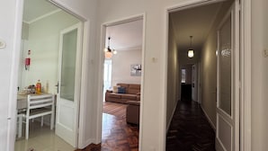Ein Flur mit Holzboden, einer weißen Tür und einem braunen Sofa im Hintergrund.