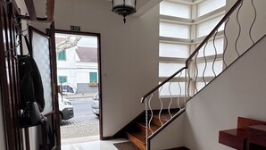 Ein geräumiger Flur mit einer Holztreppe, einer Hängelampe und einem Teppich.