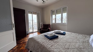 Ein Schlafzimmer mit Bett, Stuhl, Fenster und Tür.