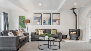 A modern living room with two grey sofas, a coffee table, and a fireplace. - Tihi Time - Spa Pool, Games Room, Sleeps 10 (Rotorua)