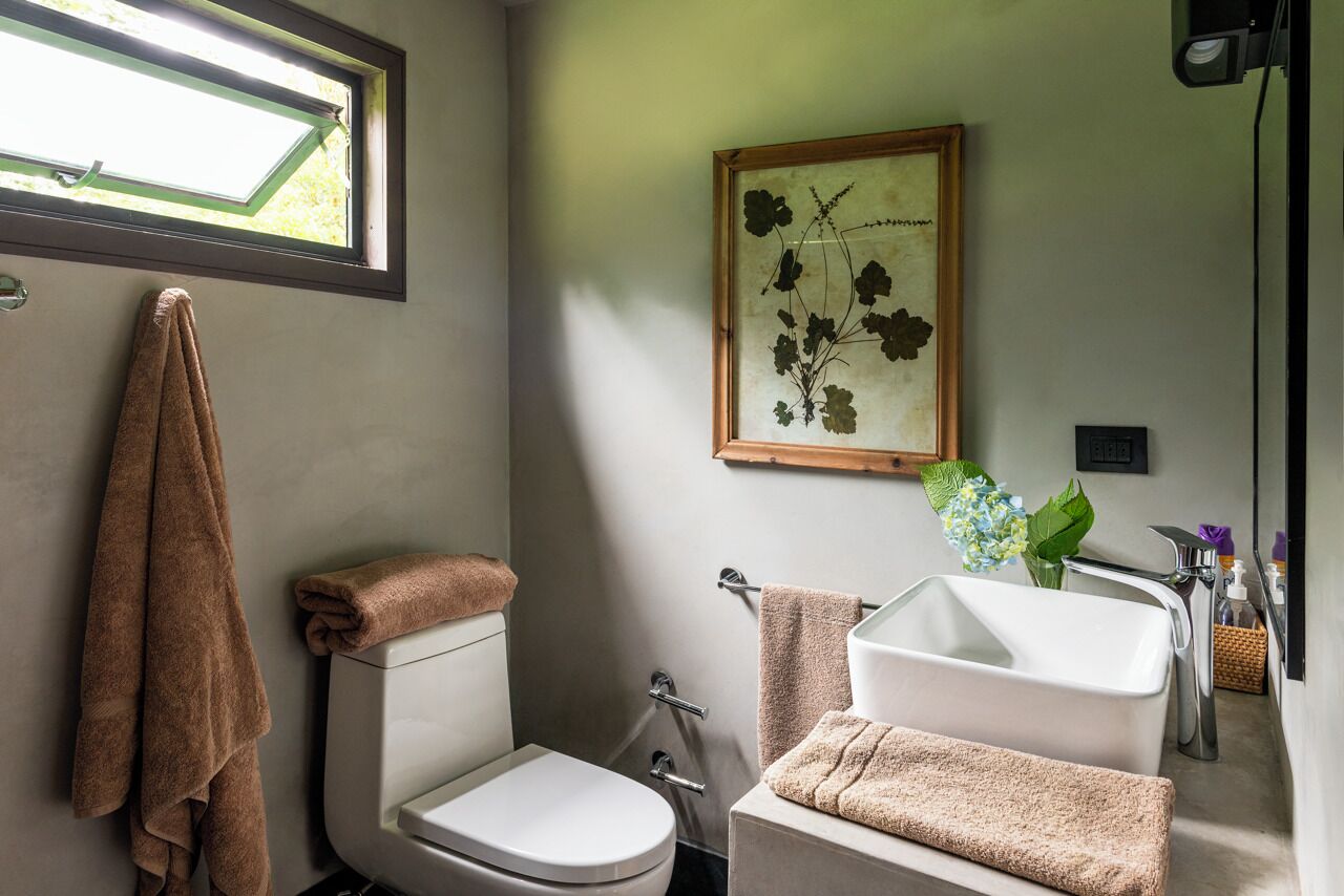 Un baño con inodoro, lavamanos y perchero para toallas.