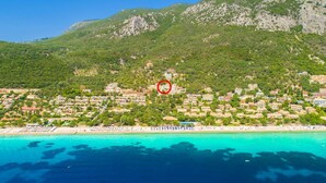 Un pueblo costero con playa, edificios y montañas al fondo.
