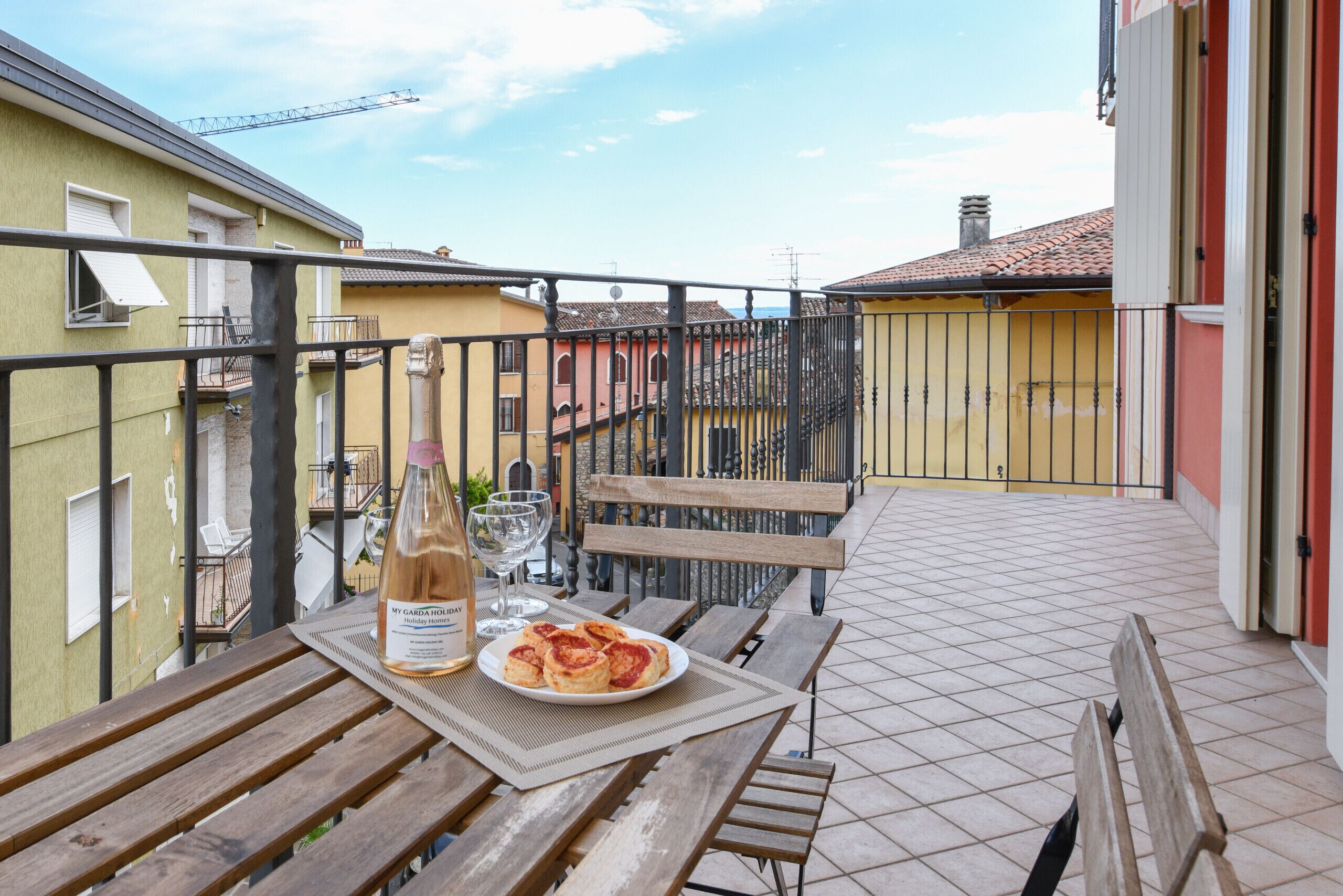 Ein Balkon mit Tisch, einer Flasche und einem Teller mit Essen.