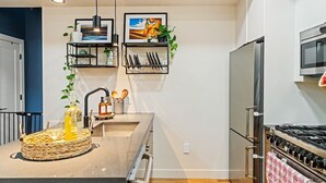 Et moderne køkken med en central ø, rustfrie hvidevarer og dekorative planter.