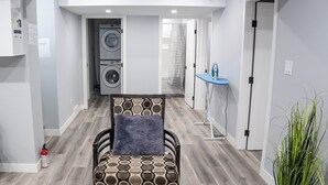 Ein modernes Interieur mit einem gemusterten Sessel, einer Waschmaschine und einem blauen Bügelbrett.