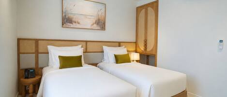 A hotel room with two beds, a painting, an air conditioning unit, and a bedside table with a phone.