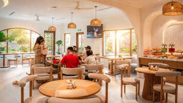 Um restaurante com mesas redondas, cadeiras e uma área de buffet.