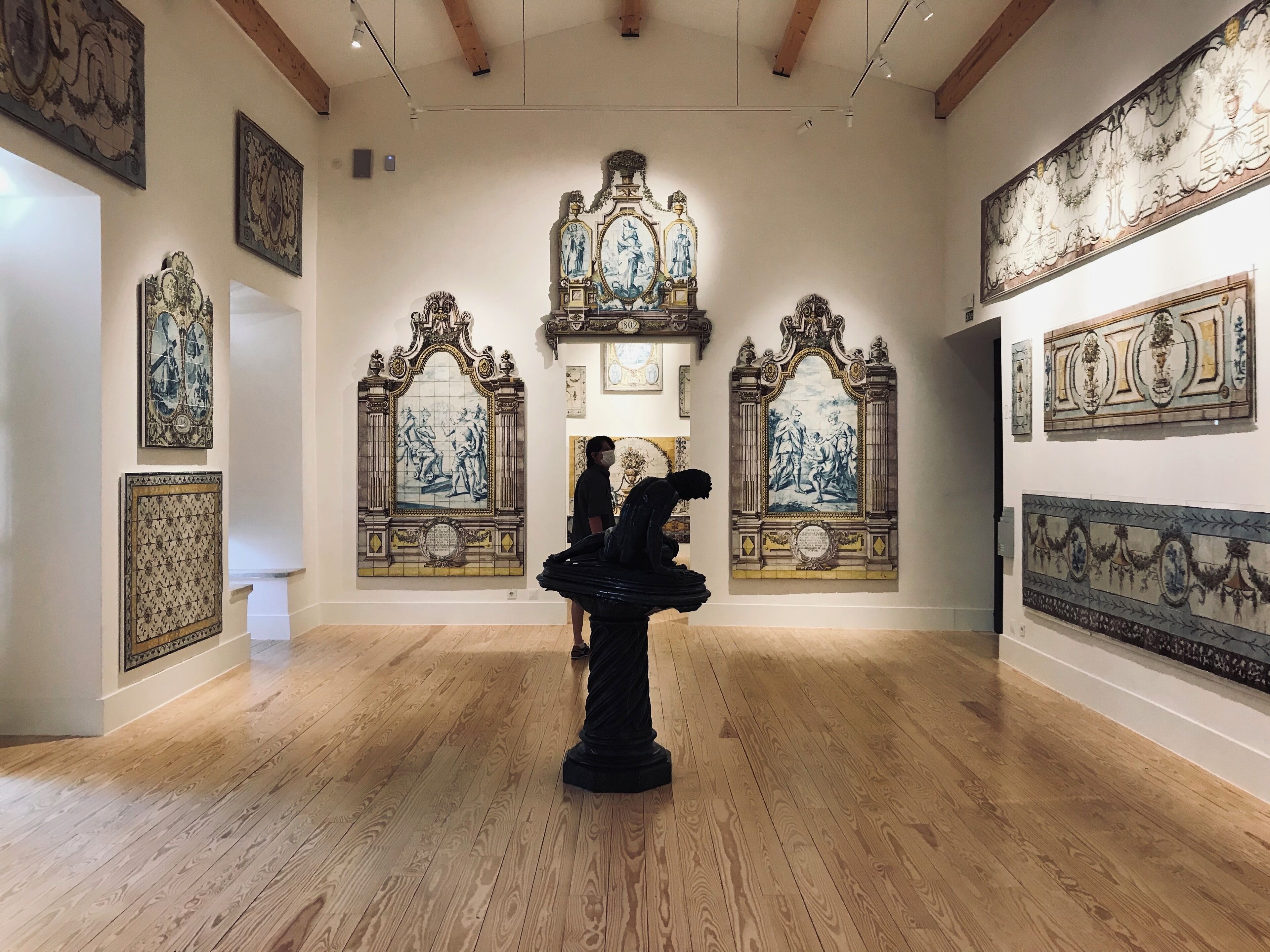 An art gallery with wooden floors and classical paintings on the walls.