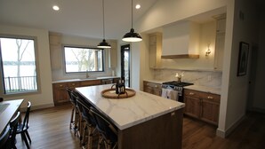 A modern kitchen with a large island, wooden cabinets, and a view of the outdoors. - Amazing 6-bedroom Lakefront Home in Cassopolis, MI (Cassopolis)