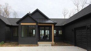 A modern two-story house with a dark exterior, large windows, and a covered front porch. - Amazing 6-bedroom Lakefront Home in Cassopolis, MI (Cassopolis)