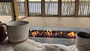 A cozy outdoor seating area with a fire feature, wooden railings, and a view of a lake and trees. - Amazing 6-bedroom Lakefront Home in Cassopolis, MI (Cassopolis)