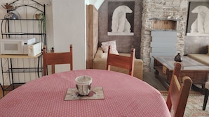 A dining area with a round table, chairs, a red tablecloth, a white bowl on a coaster, a stone wall, and a hanging light fixture. - AU COCON SAVOIE☃️❄️ Cosy valley accommodation for the clever😃⛷️🏂🏻 (La Plagne Tarentaise)