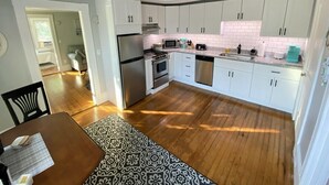 Uma cozinha moderna com armários brancos, eletrodomésticos de aço inoxidável e um tapete estampado.