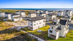 Una zona residenziale costiera con case moderne bianche, alcune dotate di balconi, e una vista aperta sull'oceano.